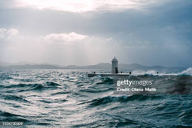 lighthouse amidst ocean waves during stormy weather and dramatic sky in zadar, croatia - ponton photos et images de collection