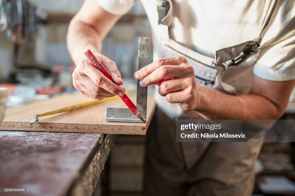 Carpenter Measuring and Marking Wood with Precision Tools in Workshop