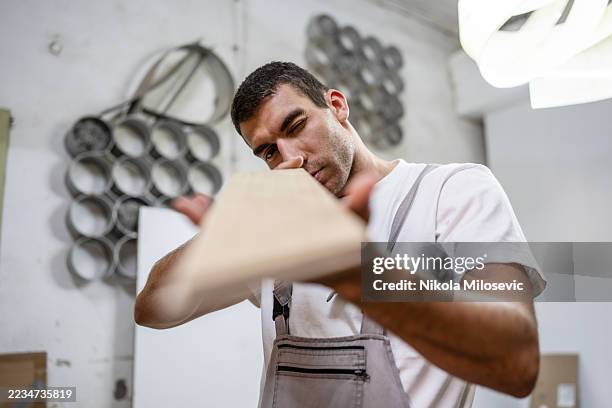 focused carpenter precisely analyzing a wooden plank in a workshop setting - floorboard stock pictures, royalty-free photos & images