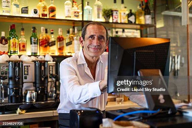 mature bartender showing cash register screen at the bar counter - cash register stock pictures, royalty-free photos & images