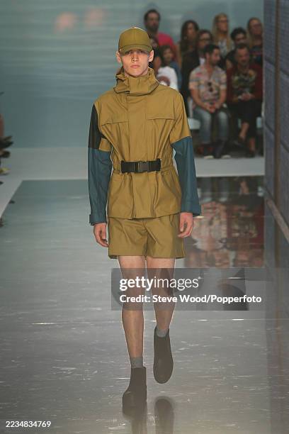 Model walks the runway at the Hunter Original show during London Fashion Week Spring/Summer 2015, he wears khaki Burmuda shorts and a matching short...