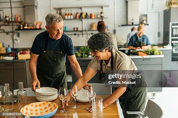 elderly woman and man setting table after cooking class - setting the table stock pictures, royalty-free photos & images