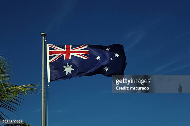 australian flag in the wind against blue sky - real photo, not cgi - pole stock pictures, royalty-free photos & images