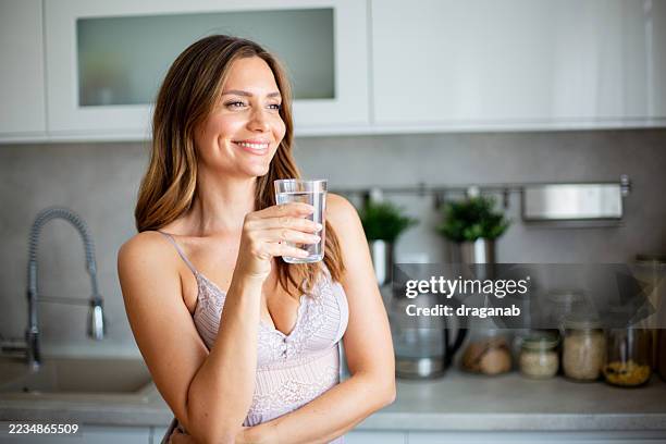 young woman drinking fresh water in the kitchen - freshwater stock pictures, royalty-free photos & images