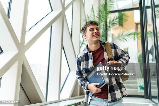 étudiant heureux marchant dans le couloir de l’université - représentation masculine photos et images de collection