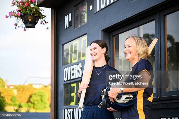 side view successful female batsmen standing by score board after winning - catchers mitt stock pictures, royalty-free photos & images