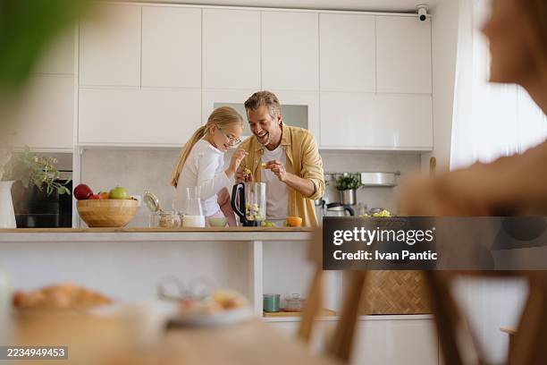 father and daughter preparing a smoothie in the kitchen - couple making breakfast stock pictures, royalty-free photos & images
