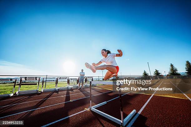 collegiate heptathlete clears hurdle on outdoor track - hurdle stock pictures, royalty-free photos & images