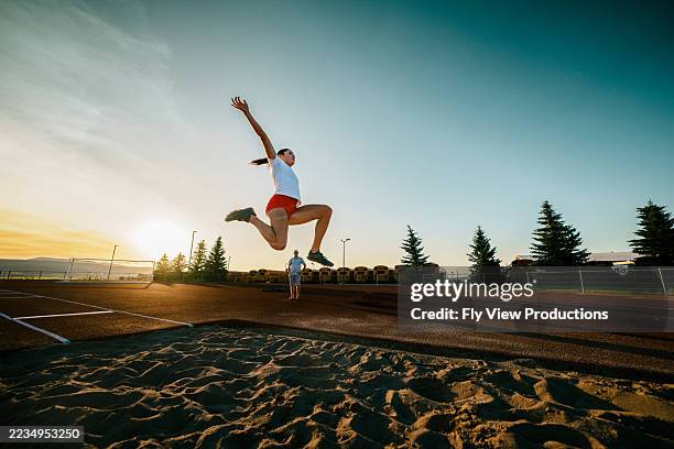 track and field athlete practicing long jump at sunset - verspringen stockfoto's en -beelden
