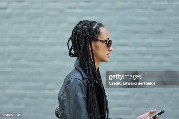 Guest wears long box braids, narrow oval brown-tinted sunglasses from Valentino, outside Kate Barton, during New York Fashion Week, on September 11,...