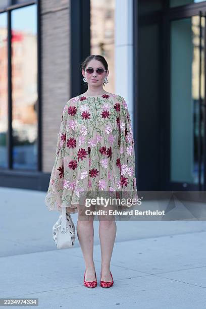 Guest wears hair pulled back into a low bun, oval pink-tinted sunglasses with thin frames, large silver spiral hoop earrings, a small white...