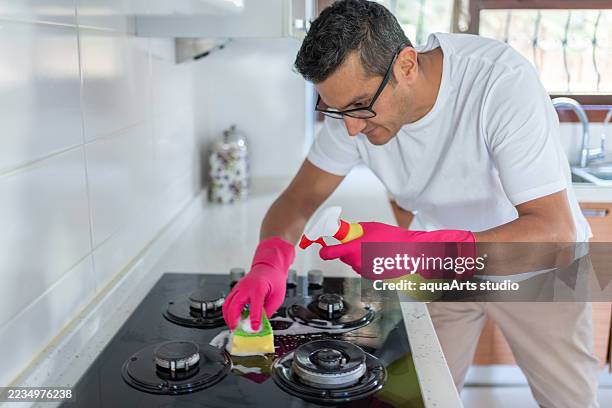 cleaning gas stove with sponge at kitchen - placa de fogão vitrocerâmica imagens e fotografias de stock