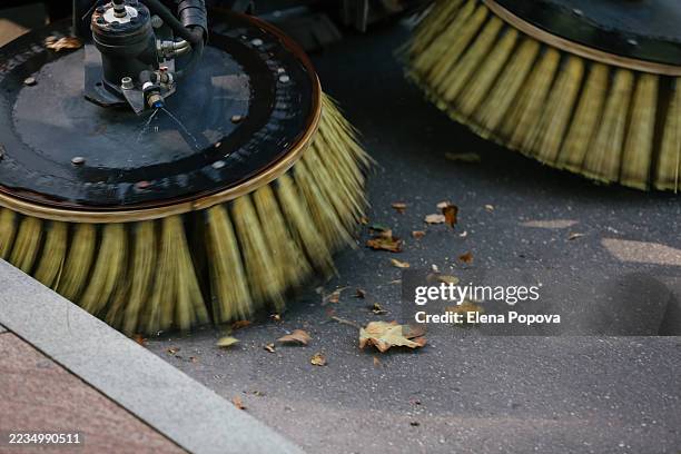cleaning machine sweeping up fallen autumn colored leaves in the city street - sweeping stock pictures, royalty-free photos & images