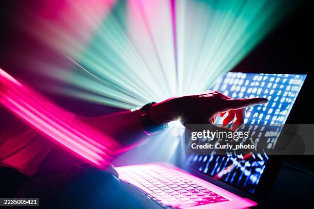 a person's hand is reaching out to touch a laptop screen displaying lines of code, while vibrant pink and green light beams create a sense of dynamic motion. - promo code stock pictures, royalty-free photos & images