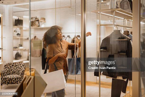 elegant customer looking at clothes in a fashion boutique - vestido preto imagens e fotografias de stock