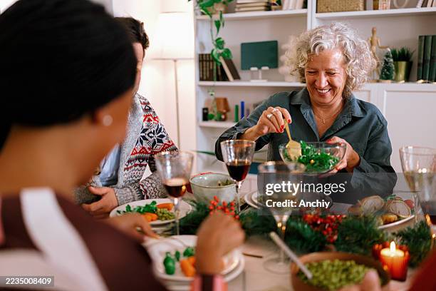 miembros de la familia pasando platos en la mesa de la cena navideña - cena con amigos fotografías e imágenes de stock
