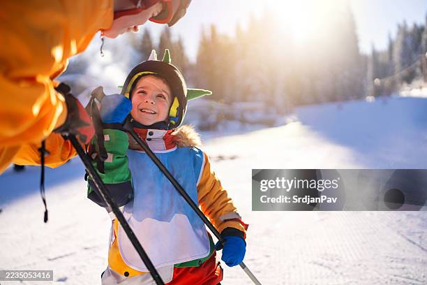 child enjoying ski lesson with instructor in sunny snowy mountain setting - family skiing stock pictures, royalty-free photos & images