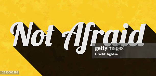 not afraid - text with long shadow on textured yellow background - gritty background texture stock illustrations