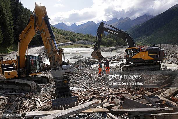 Excavator operators take a break while clearing mangled debris, including the remains of a cow shed, from the May landslide on September 11, 2025 at...