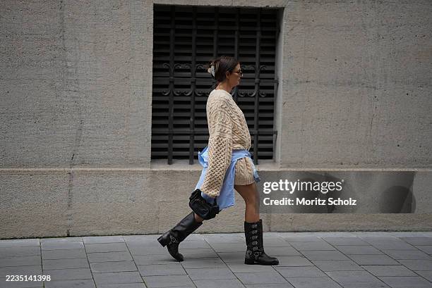 Anna Winter is seen wearing an oversized beige cable knit sweater with a chunky texture and long, relaxed sleeves from The Frankie Shop; a light blue...