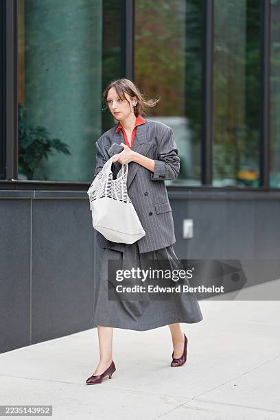 Guest wears brown hair pulled back into a low loose bun with wispy bangs and face-framing strands, a thin silver necklace, a slouchy white woven mesh...