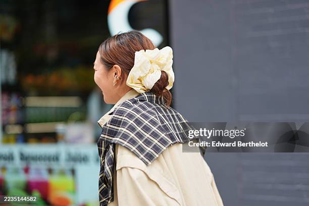 Guest wears medium brown hair with auburn highlights pulled into a low bun secured with an oversized pale yellow scrunchie, a small gold ear cuff and...