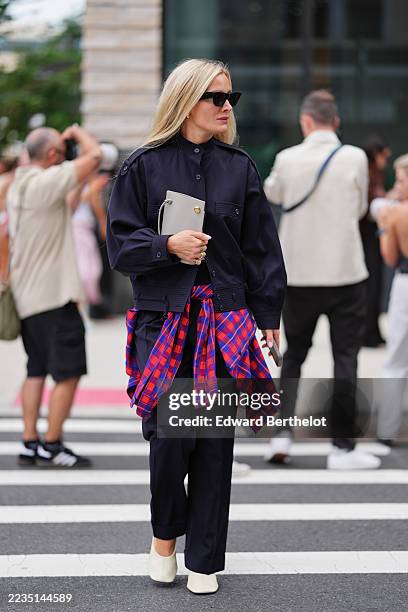 Guest wears long straight blonde hair worn loose, black angular cat-eye sunglasses, small gold hoop earrings and gold rings, a small rectangular...