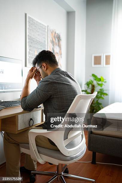 stressed young man having headache while working from home office - cognitive computing stock pictures, royalty-free photos & images