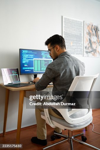 Computer programmer writing code on computer at home office Computer programmer writing code on computer at home office