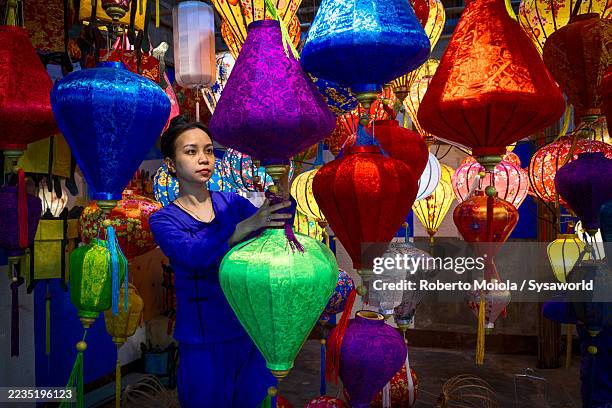 woman arranging colorful lanterns in a shop - vietnamese culture stock pictures, royalty-free photos & images