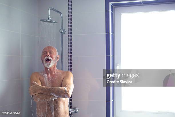 senior man taking a shower in the morning - douche stockfoto's en -beelden