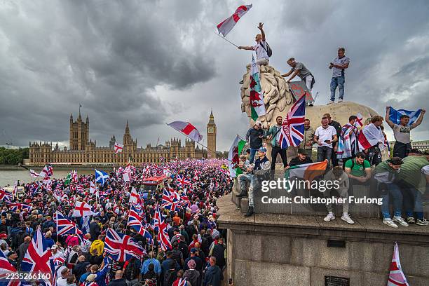Protesters wave Union Jack and St George's England flags during the "Unite The Kingdom" rally on Westminster Bridge by the Houses of Parliament on...