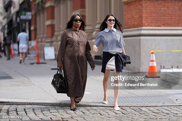 Guest wears straight shoulder-length black hair parted in the middle, black oversized rectangular sunglasses, a structured black leather top-handle...