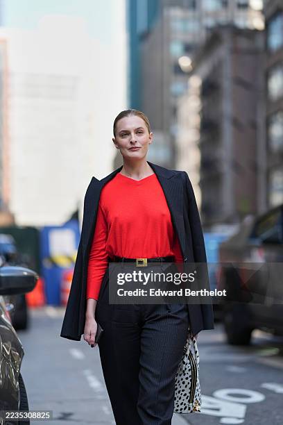 Guest wears hair slicked back into a low bun, a white leather top-handle bag with black spotted print and gold hardware, a charcoal pinstriped blazer...