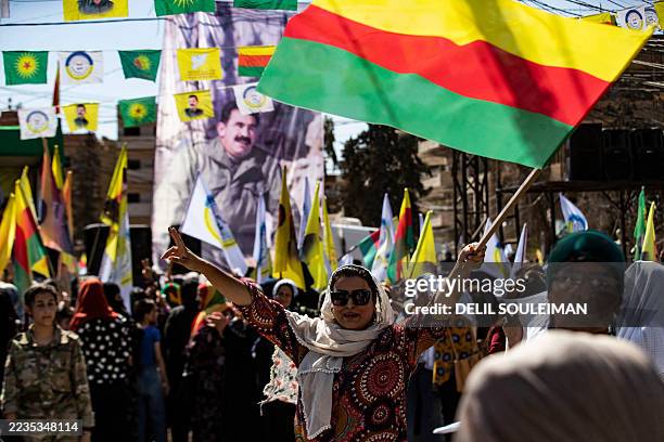 Syrian Kurds lift placards and flags during a rally calling for an autonomous administration and Kurdish rights in Syria's predominantly-Kurdish...