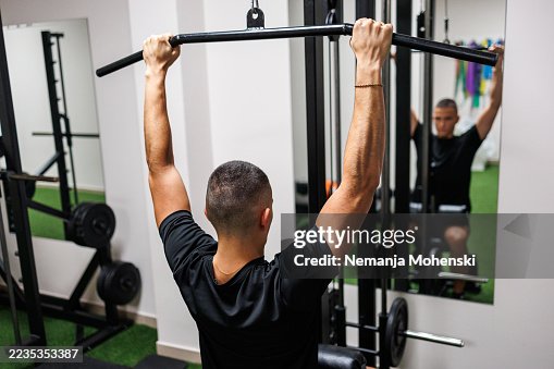 Man Using Lat Pulldown Machine in a Gym for Strength Training Man Using Lat Pulldown Machine in a Gym for Strength Training