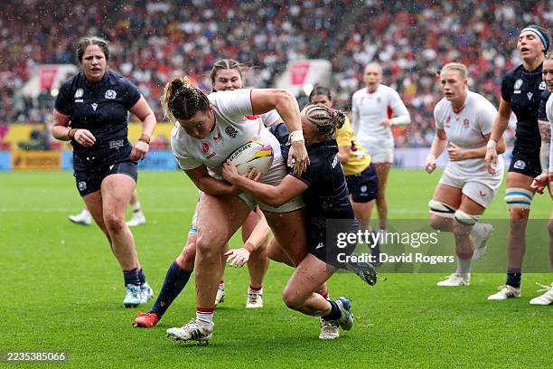 Kelsey Clifford of England runs with the ball whilst under pressure from Leia Brebner-Holden of Scotland, before going on to score her team's fourth...