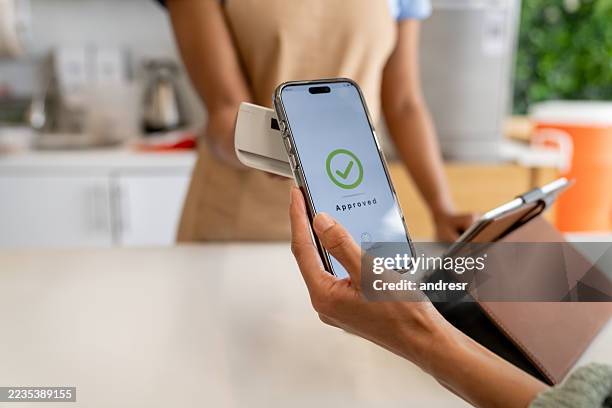 primer plano de un cliente que realiza un pago móvil en una cafetería - comunicación de campo cercano fotografías e imágenes de stock