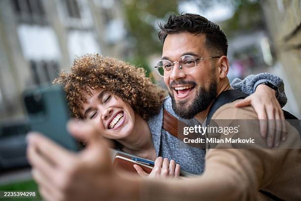 fröhliche universitätsstudenten, die ein selfie vor dem college machen - studierendenvertretung stock-fotos und bilder