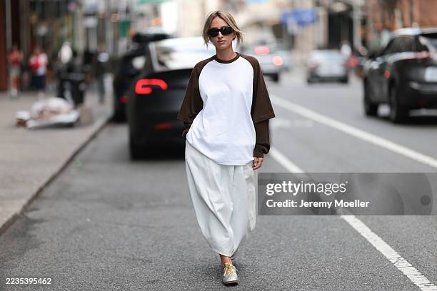 Isabelle Allain is seen wearing a two-toned baseball-style shirt. The body of the shirt is white, and the sleeves are a deep brown color. The shirt...