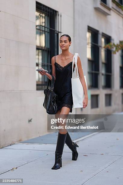 Guest wears hair slicked back into a low bun, a slouchy black leather shoulder bag with short rounded handles carried in the crook of the arm, a tall...