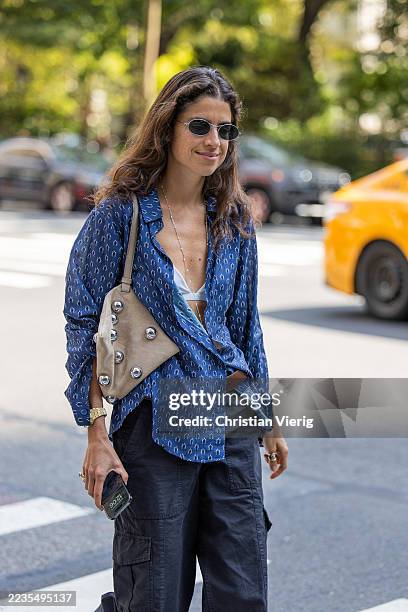 Leandra Medine wears blue blouse, beige bag, navy pants outside Altuzarra during New York Fashion Week on September 13, 2025 in New York City.