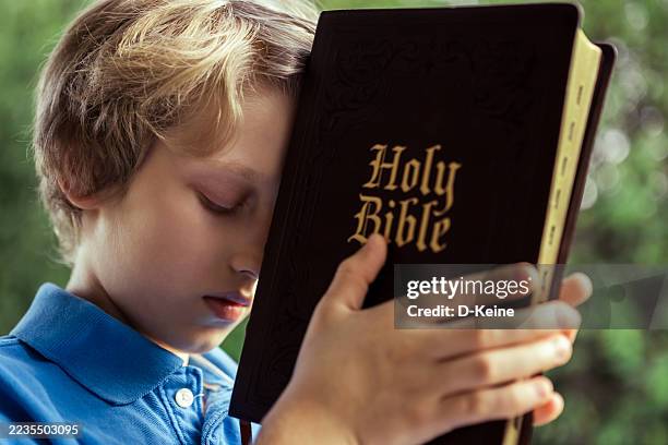 niño orando con la santa biblia en las manos - texto religioso fotografías e imágenes de stock