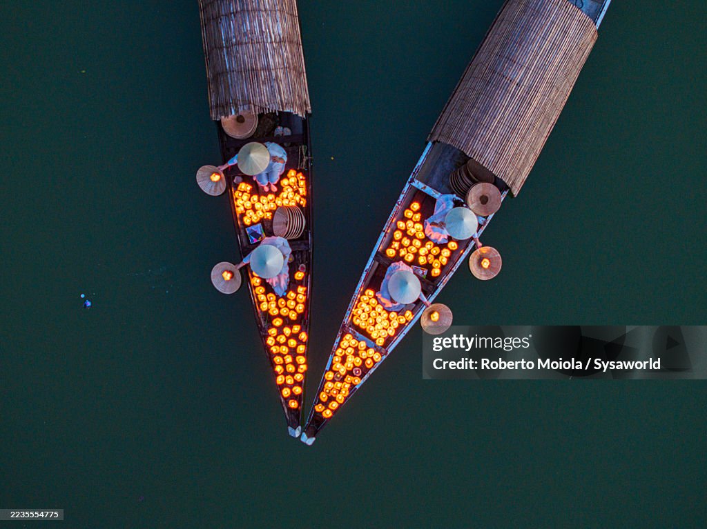 Women on boats release candle lanterns on river