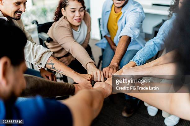 persone con le mani unite durante la sessione di gruppo di terapia - servizio sociale foto e immagini stock