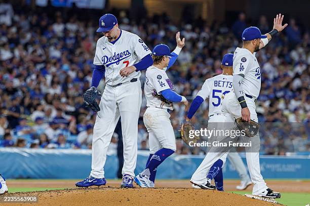 Los Angeles Dodgers third base Enrique Hernández and Los Angeles Dodgers second base Miguel Rojas gesture towards an approaching relief pitcher to...