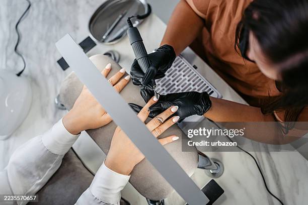 femme d’âge moyen se faisant limer les ongles par une technicienne des ongles dans un salon de beauté - lustrer photos et images de collection