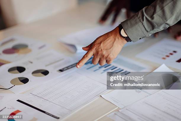 primer plano de manos revisando datos y gráficos en una mesa - calificación fotografías e imágenes de stock