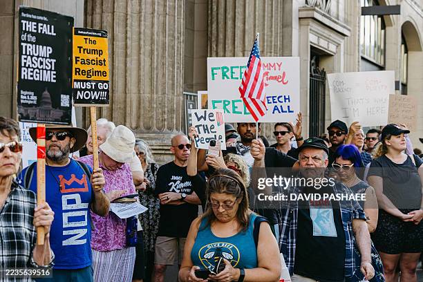 Protesters hold signs reading "The Trump Fascist Regime Must Go Now!!!," "Free Speech 4 All," and "We the People" outside the El Capitan Theatre on...
