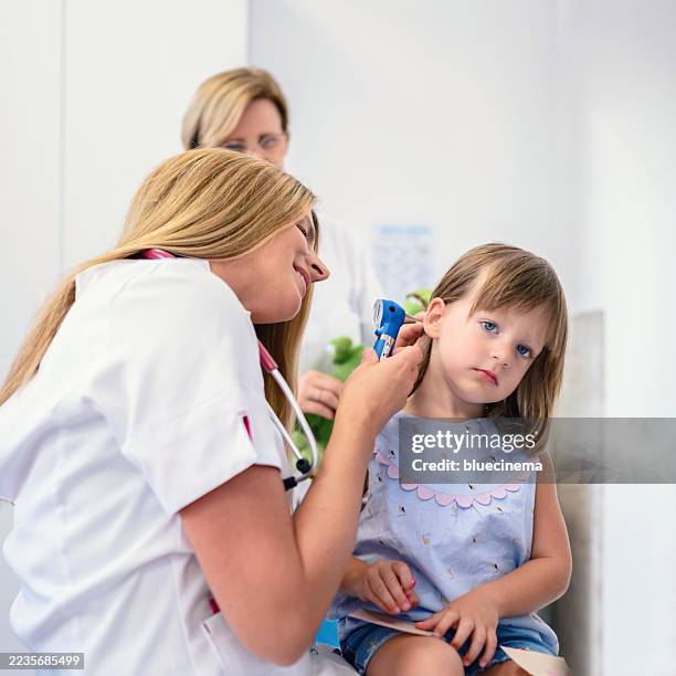 female pediatrician looking at ear of little girl using otoscope in clinic - inner ear stock pictures, royalty-free photos & images
